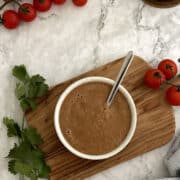 Birds Eye view of blender salsa served in a white bowl on a wooden board.