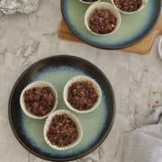 chocolate granola clusters served on a mint blue plate with a dark rim.