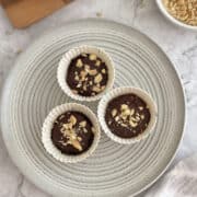 birds eye view of no-bake chocolate peanut butter mini pies/tartlets arranged on a plate, garnished with chopped peanuts.