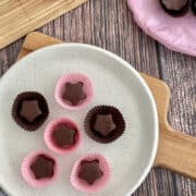 Birds Eye view of homemade star-shaped chocolates in pink and brown cases served on a plate.