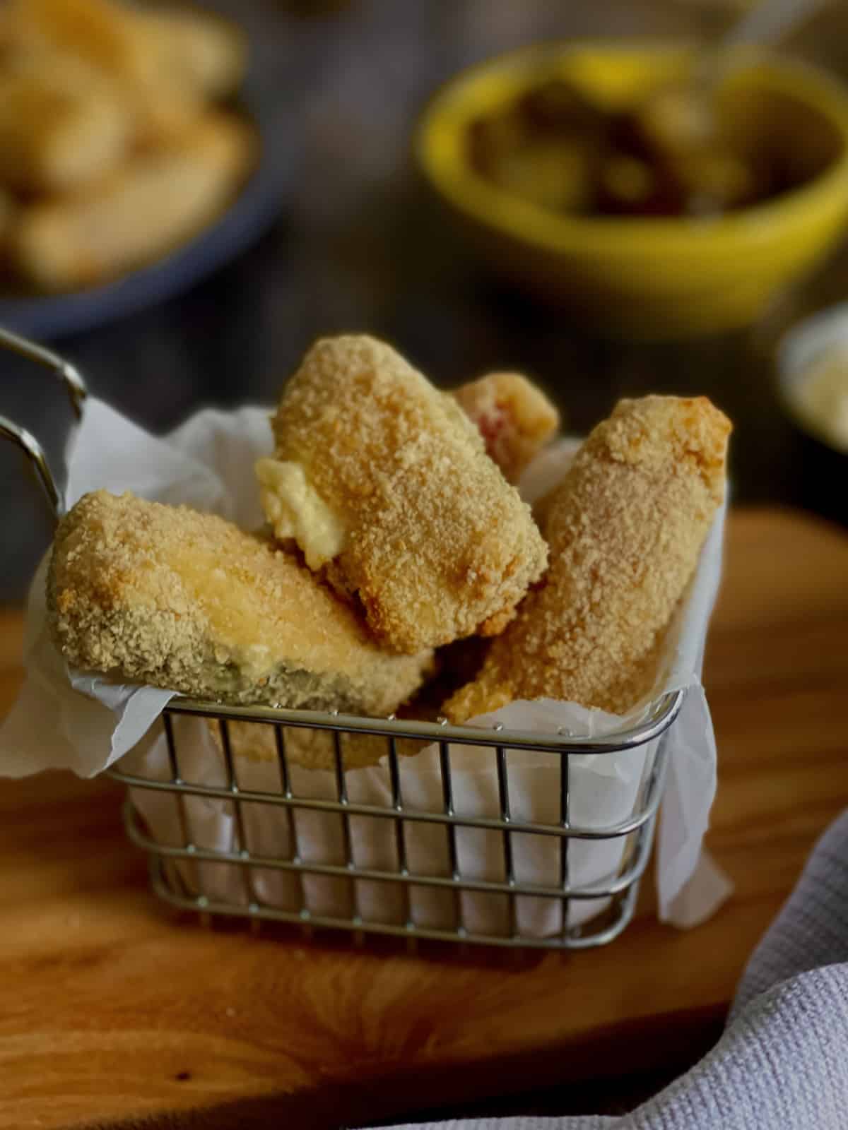 crispy and cheesy jalapeño poppers served in a basket on a board.