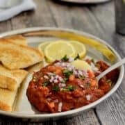 Pav bhaji topped with chopped tomatoes, onions, coriander and butter, served with toasted bread and lemon slices.