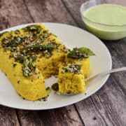 besan dhokla served on white plate, with indian mint sauce.