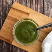 fresh mint chutney served in bowl with spoon on wooden board.