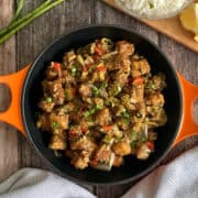 dry version of paneer Manchurian served in a black pan with orange handles, garnished with scallions/spring onions.