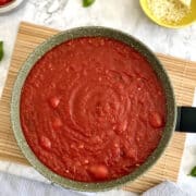 Birds Eye view of homemade simple Italian tomato sauce with plum tomatoes, served in large dark green pan.