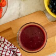 fresh berry juice in glass (birds eye view) with berries in background.