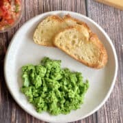 green (spinach) scrambled eggs on plate, with toast and pico de gallo salsa.