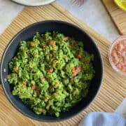 birds eye view of green veggie scrambled eggs served in pan, with pico de gallo salsa.