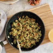 birds eye view of veggie scrambled eggs in pan, juice and salsa in background.