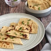 whole wheat naan served on plate, with onions on the side.