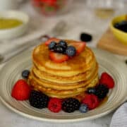 stacked fluffy and soft almond flour pancakes topped with warm maple syrup and fresh mixed berries.
