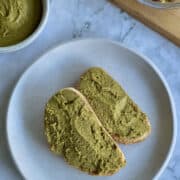 pistachio paste on sourdough, served on plate, with pistachio paste in background.