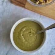 homemade pistachio paste in bowl, pistachios on the side.