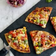 sliced air fryer naan pizza, served on black board, with salad on the side.