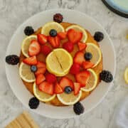 fluffy and moist gluten free lemon drizzle cake (made using almond flour) topped with fresh berries and sliced lemons.