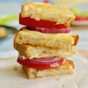 crispy sourdough grilled cheese with onions, tomato and lettuce in the background.