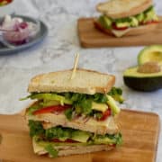crispy avocado grilled cheese sandwich, with onions, peppers and spinach, served on a board.
