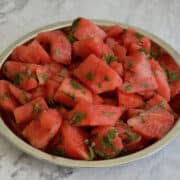 fresh vibrant watermelon chaat with mint leaves in a steel plate.