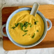 bowl of roasted creamy vegan butternut squash soup, garnished with fresh herbs.
