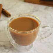 cup of pumpkin spice tea with fresh whole cinnamon sticks in background.