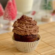 mint chocolate cupcake with chocolate cream frosting and mint chocolate ganache, with festive decorations in background.