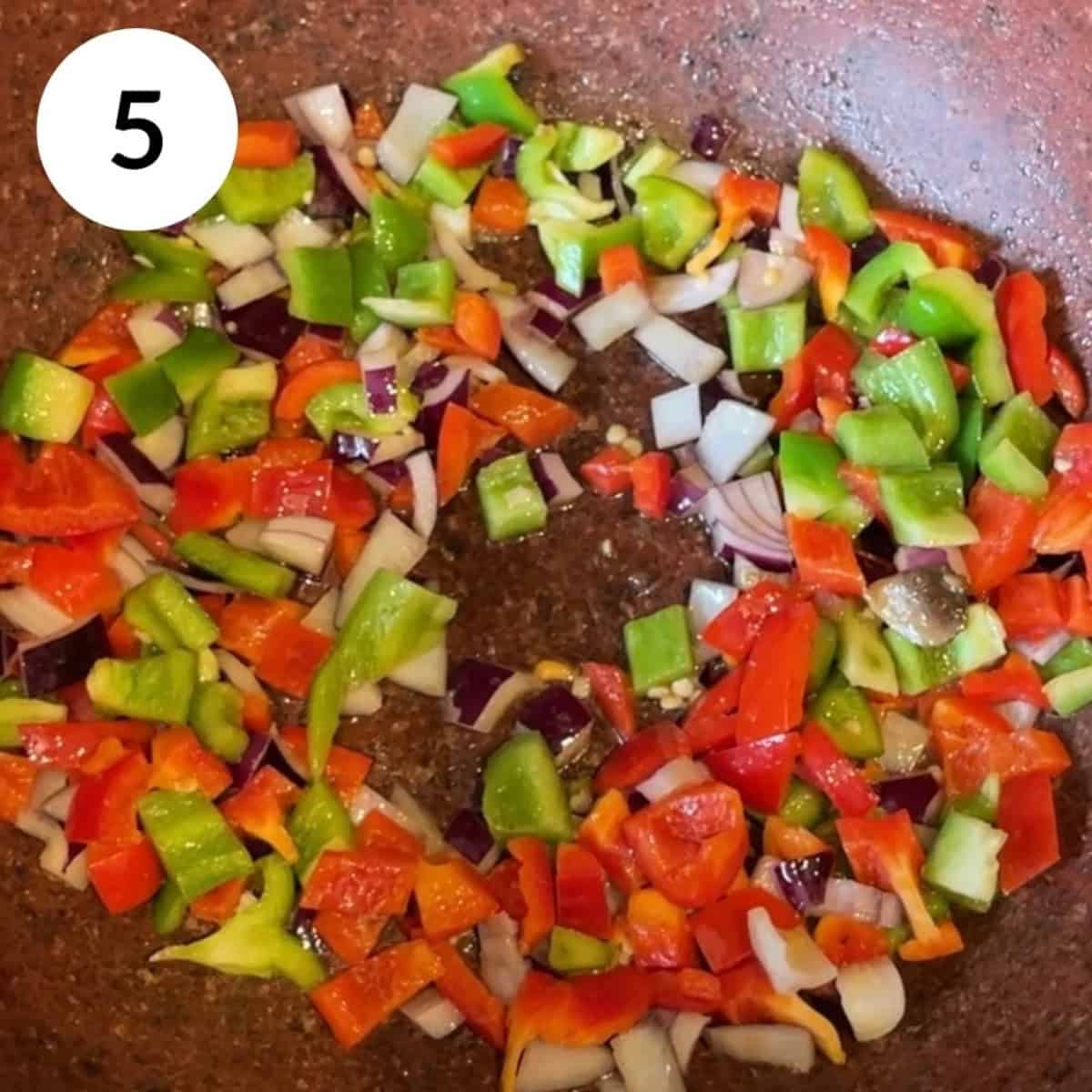 roasting the peppers and onions in a pan.
