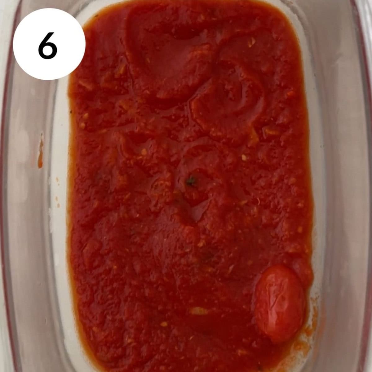 layering the base of the dish with tomato sauce.