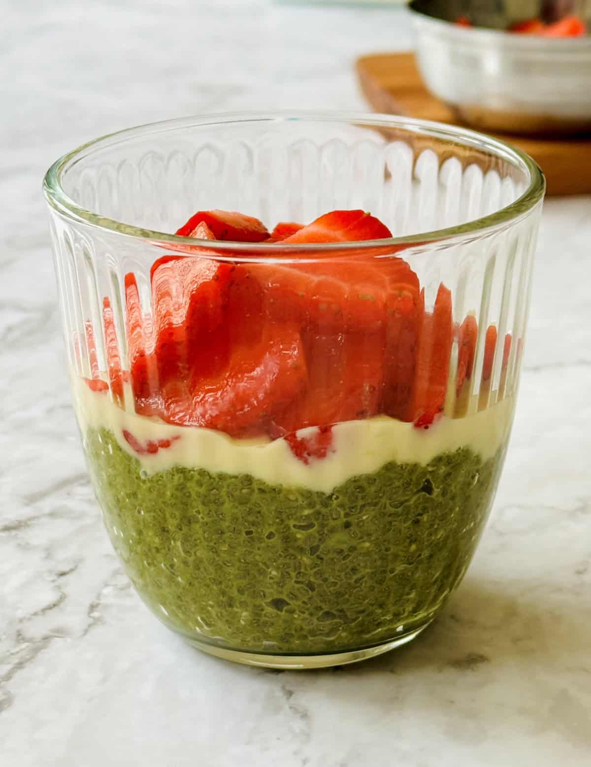 creamy matcha chia seed pudding topped with melted white chocolate and fresh strawberries.