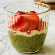 creamy matcha chia seed pudding topped with melted white chocolate and fresh strawberries, served in a glass.
