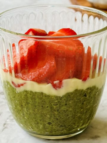 creamy matcha chia seed pudding topped with melted white chocolate and fresh strawberries, served in a glass.