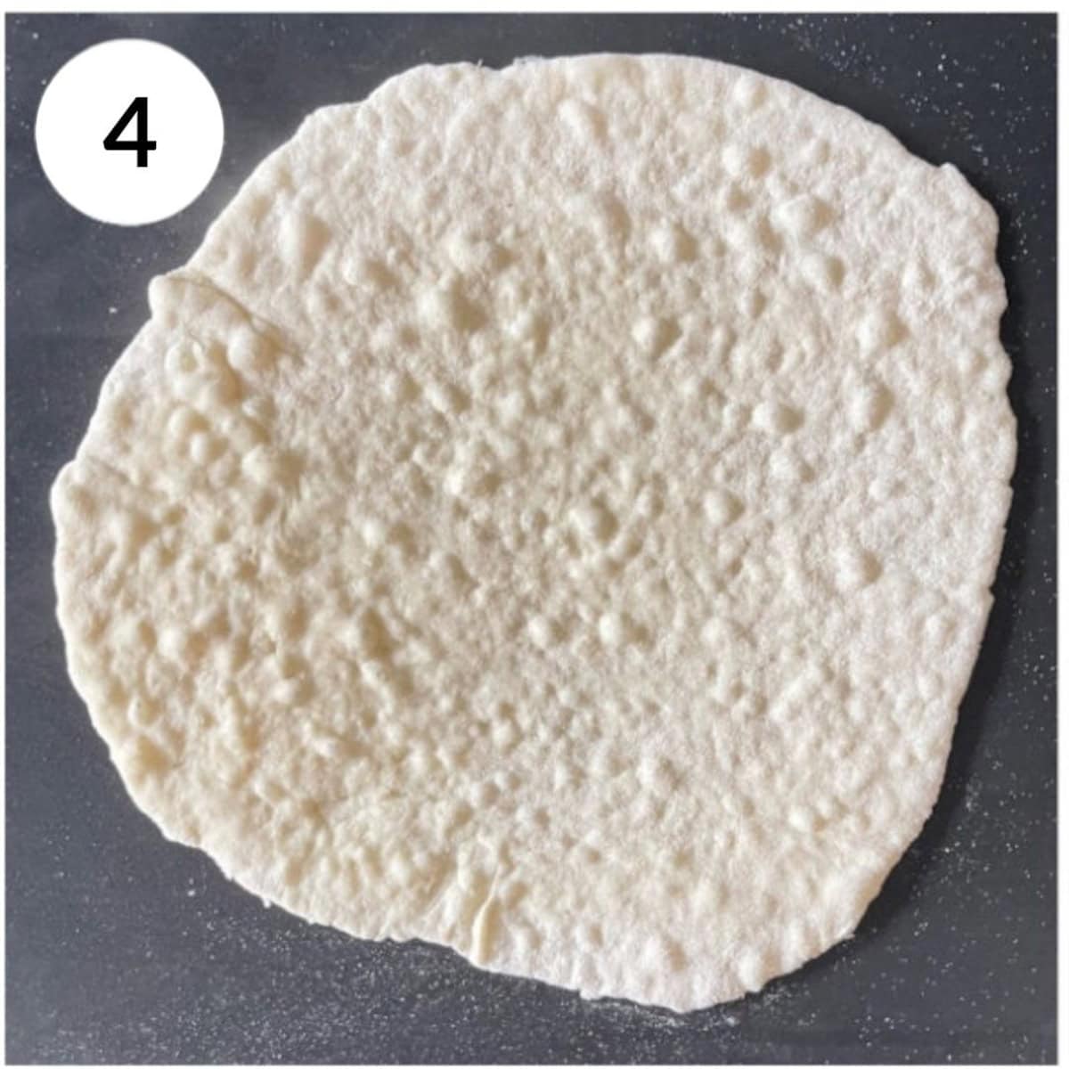 cook naan on tava/frying pan, with small bubbles forming.