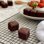 mini chocolate brownie cakes on wire rack, with a plateful of brownie cakes and strawberries.