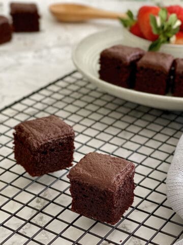 mini chocolate brownie cakes on wire rack, with a plateful of brownie cakes and strawberries.