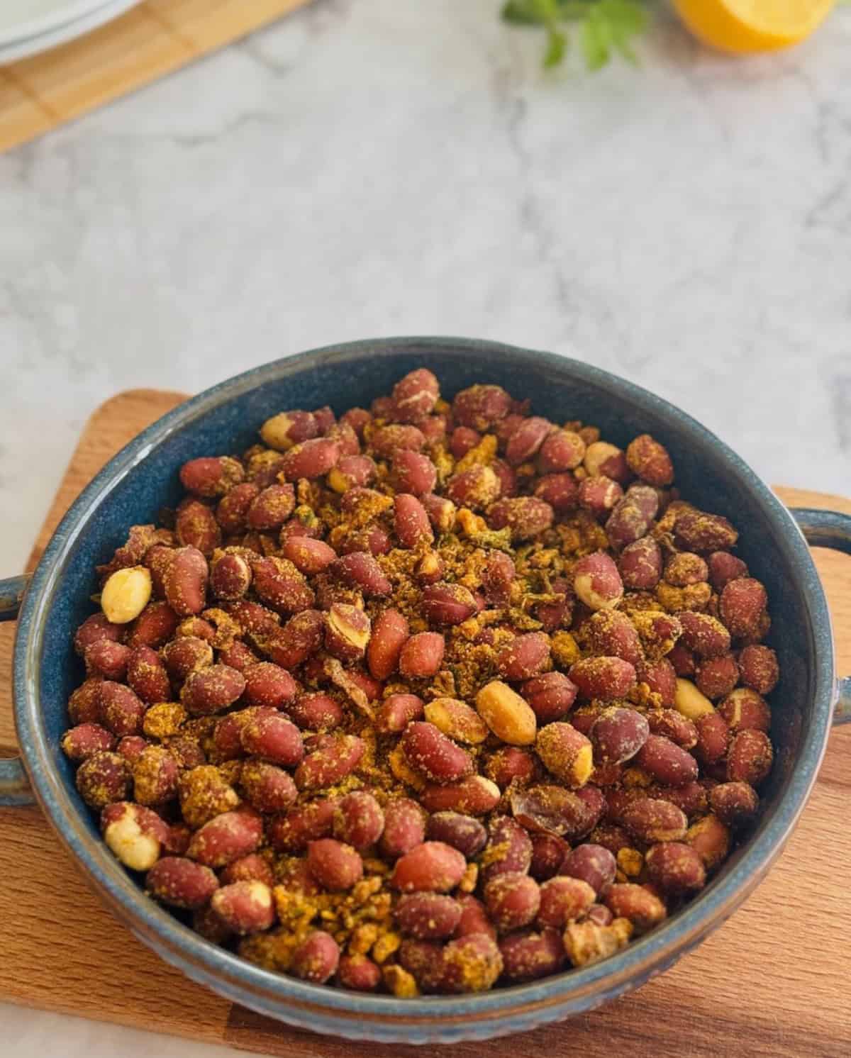 crispy masala peanuts served in blue dish, on a board.