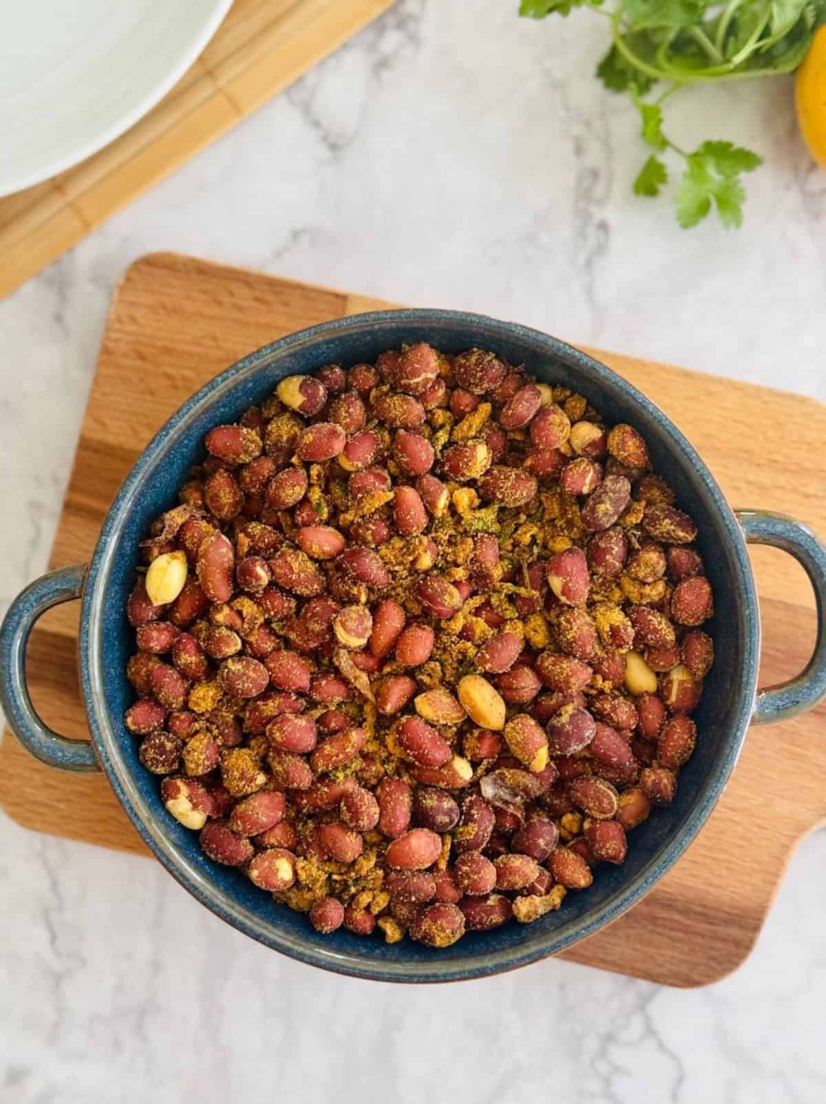 crispy masala peanuts served in blue dish, on wooden board.