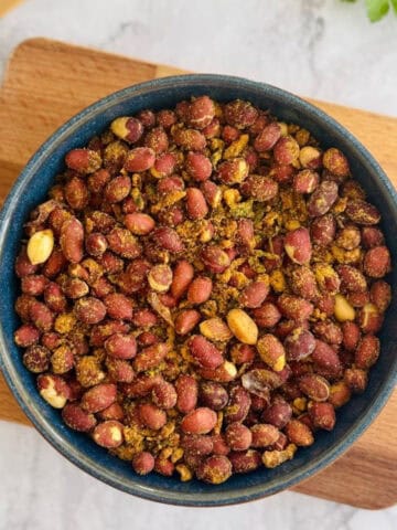 crunchy air fryer masala peanuts served in blue dish, on wooden board.