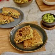 crispy masala egg paratha quarters on a plate, with fresh guacamole and salsa.
