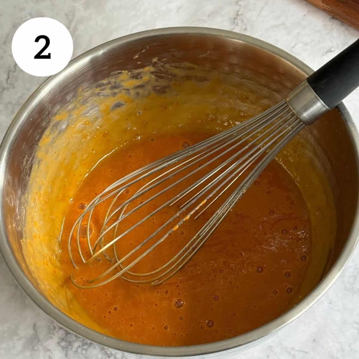 whisking wet ingredients in a bowl, including pumpkin puree, vanilla, eggs, milk.