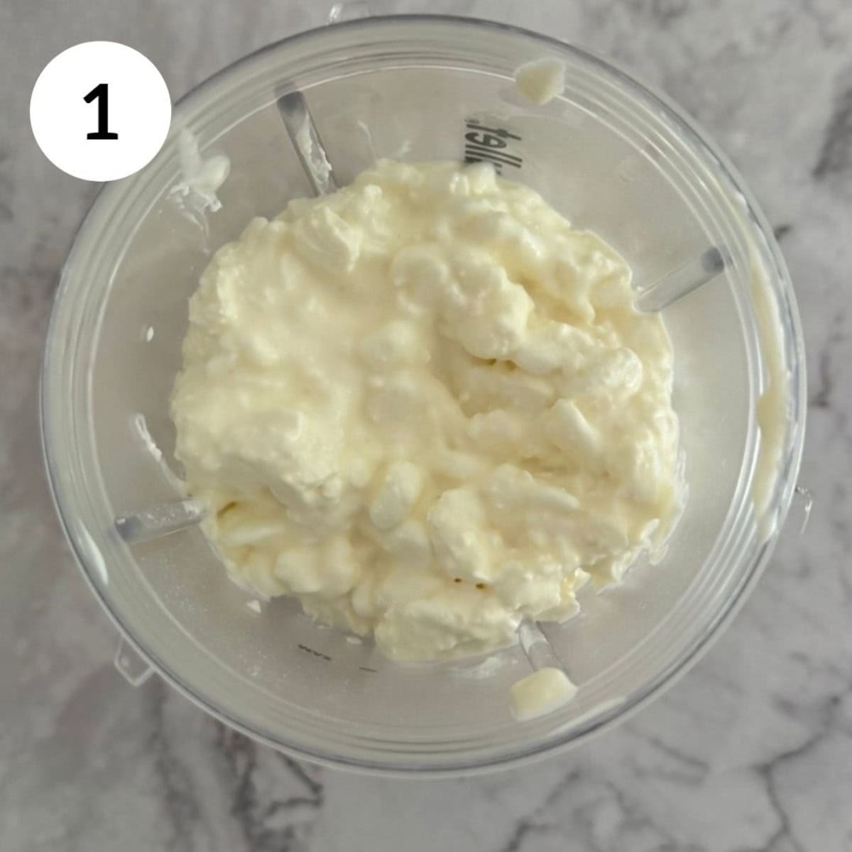 adding ingredients to the stick blender including cottage cheese, lemon juice and maple syrup.