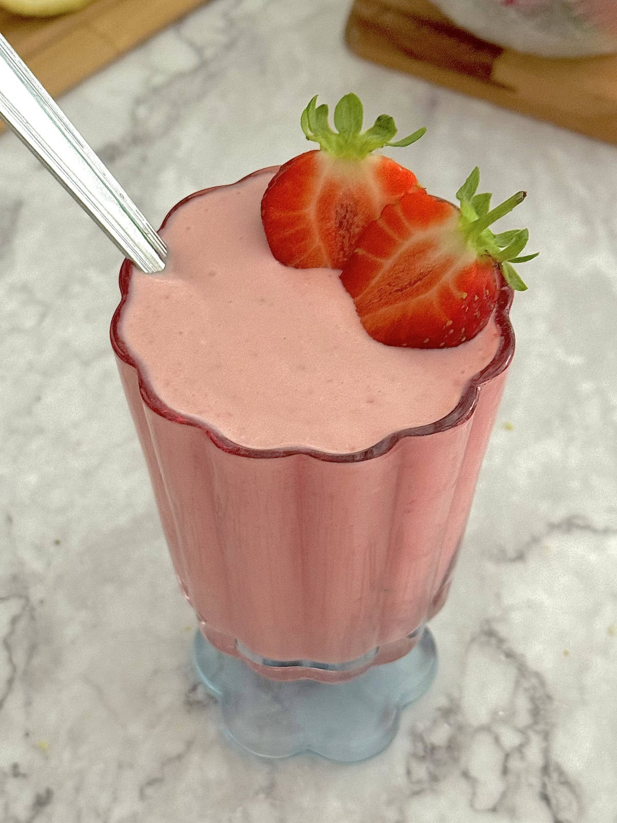 strawberry cottage cheese pudding in a flower shaped glass, with sliced strawberries on the side.