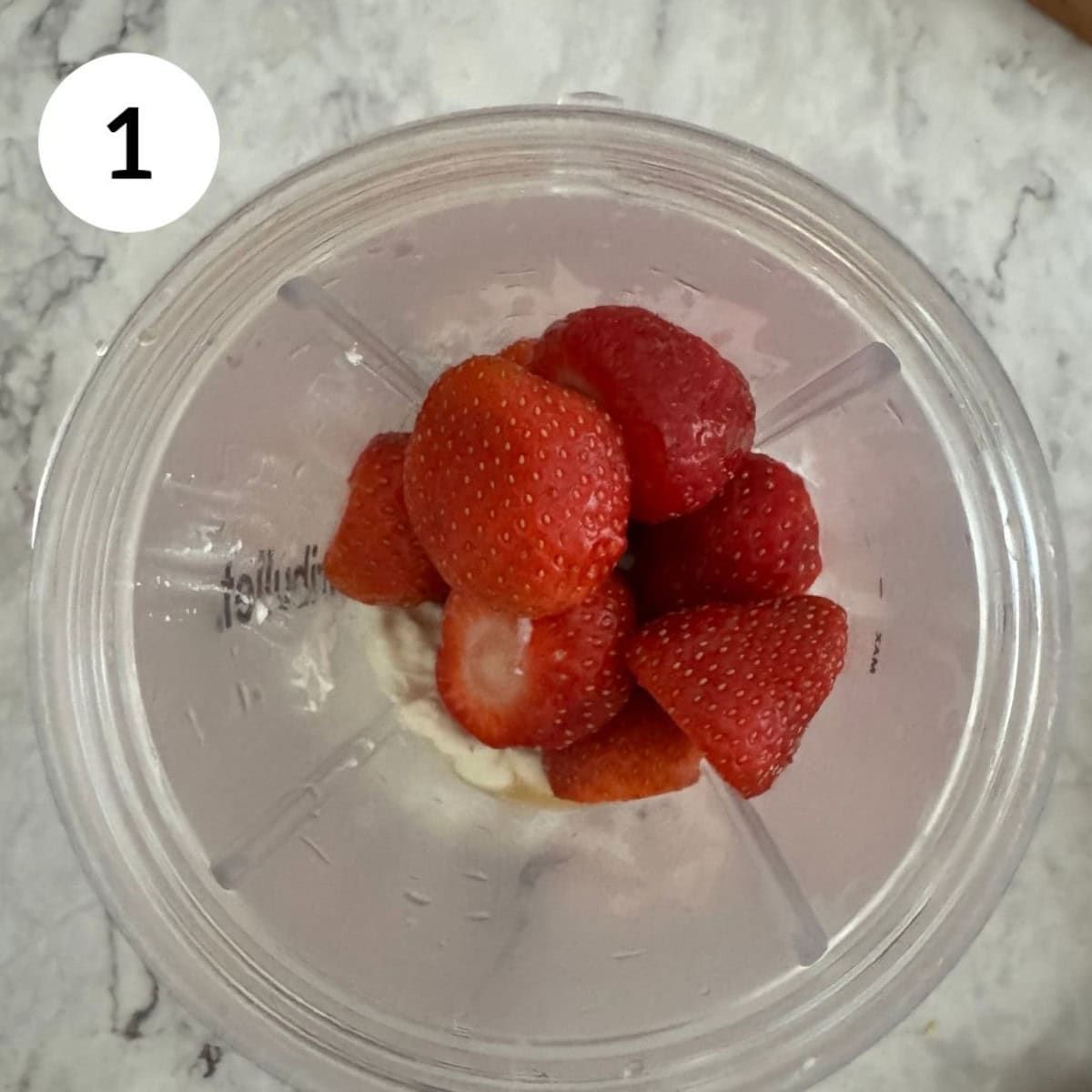 adding ingredients to the stick blender including cottage cheese, strawberries and maple syrup.