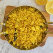 fresh poha in serving dish, with lemon wedges.