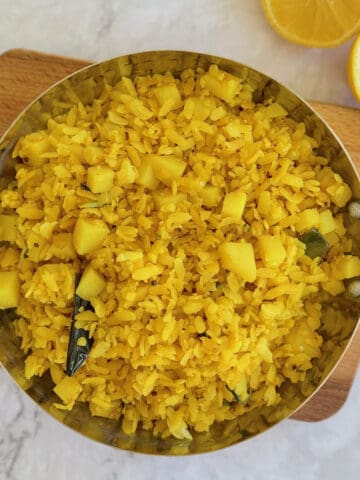 fresh poha in serving dish, with lemon wedges.