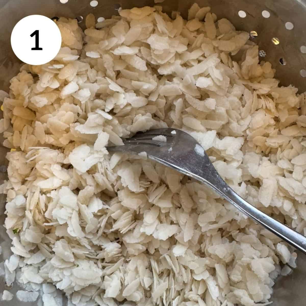 rinsing and fluffing poha (flattened rice flakes) with fork.