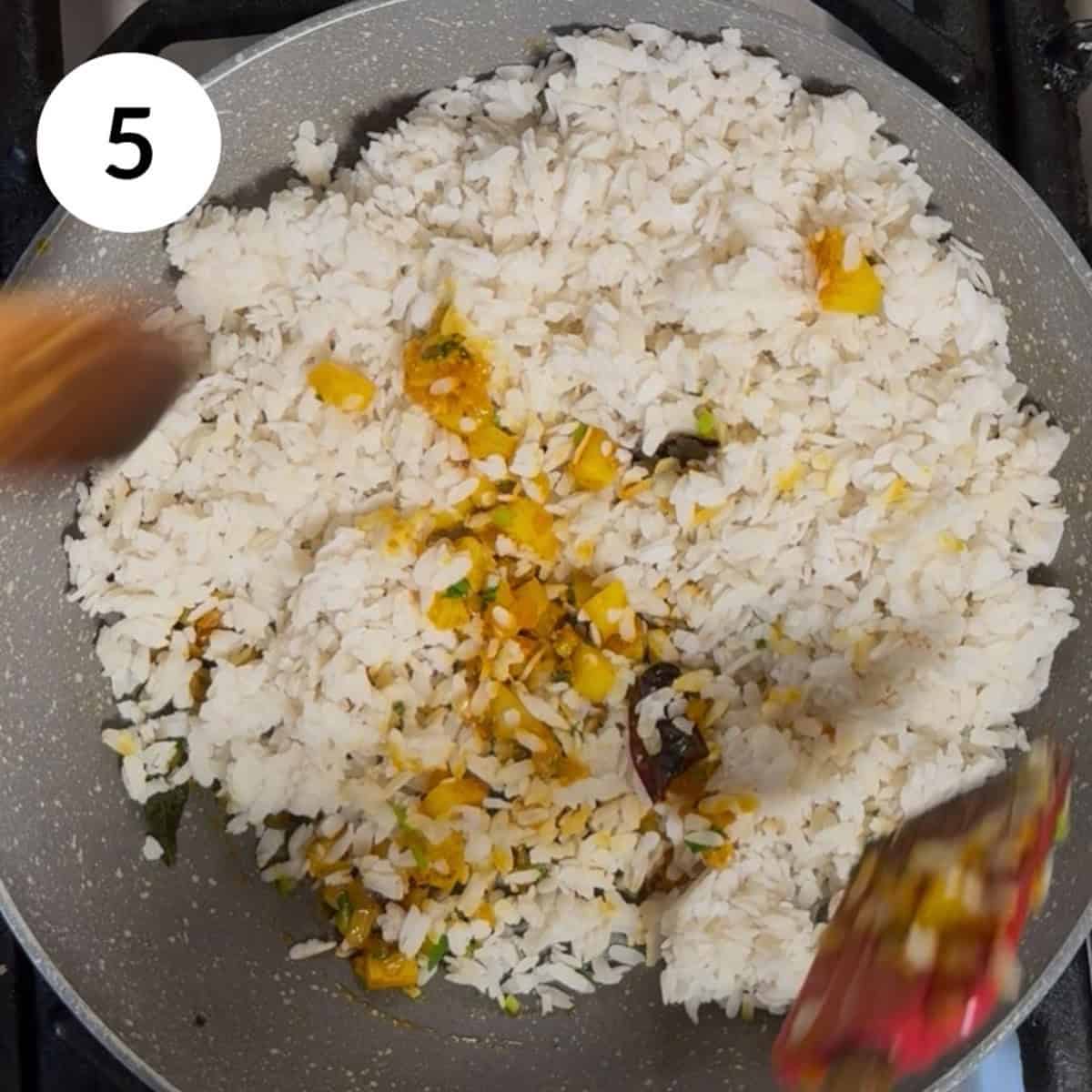 adding the rinsed poha and mixing to coat with spices.