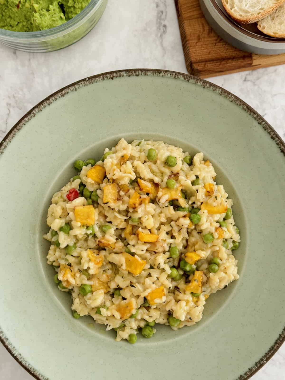 roasted pumpkin and pea risotto served in blue plate.