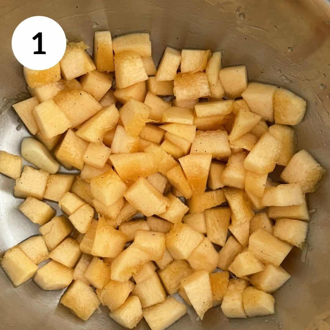 chopped pumpkin in bowl, with seasoning and garlic.