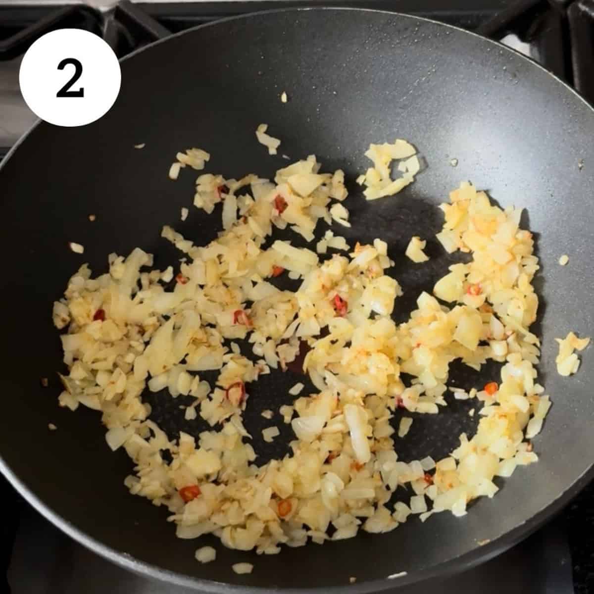 cooking garlic, onions and chillies in pan.